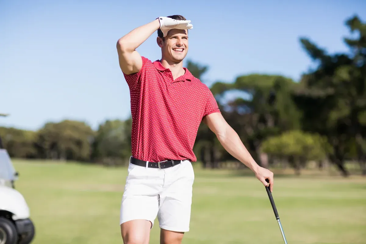 Smiling golfer shielding eyes from sun - low testosterone symptoms and treatment