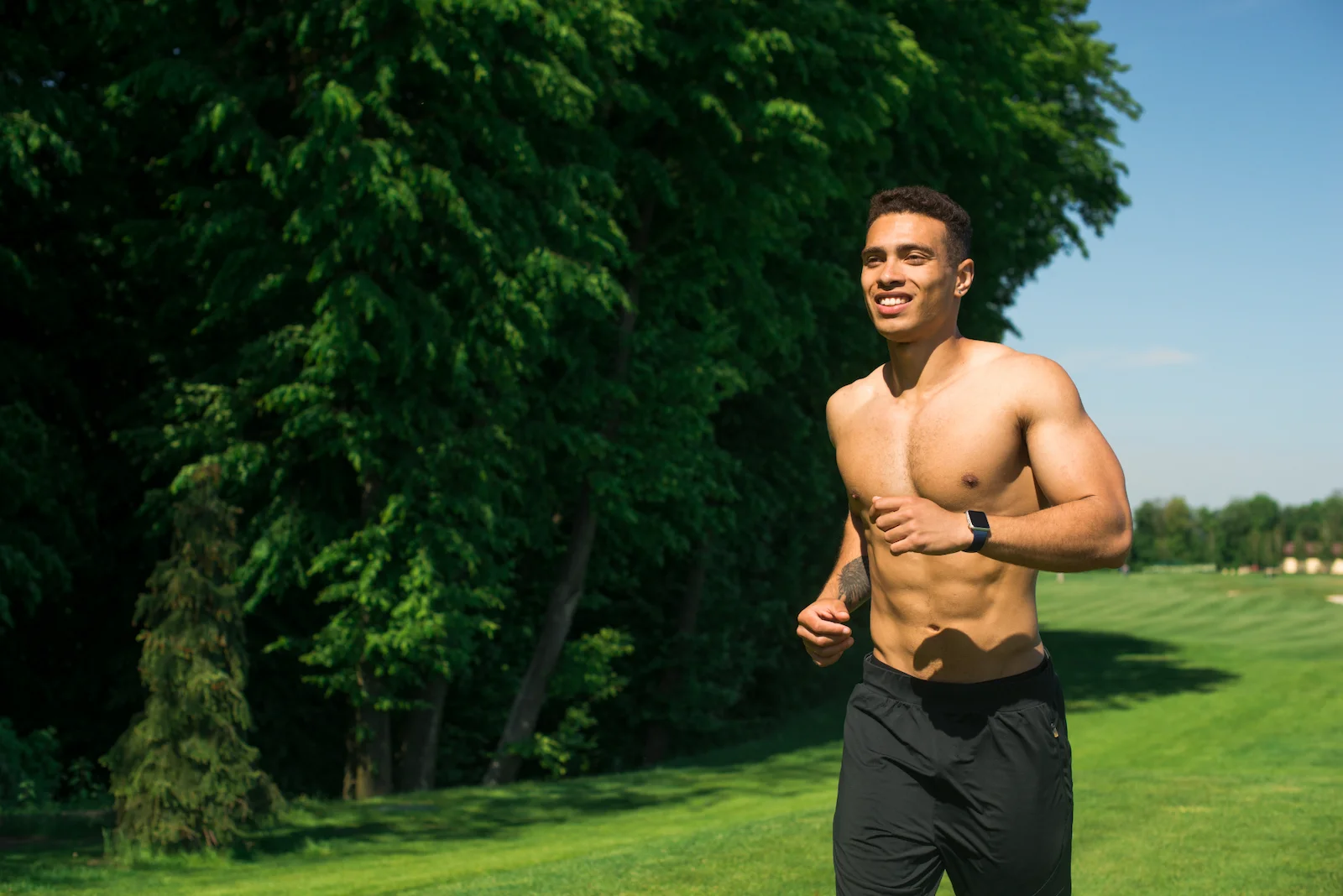 Athletic black man running outdoors - TRT muscle growth and strength benefits